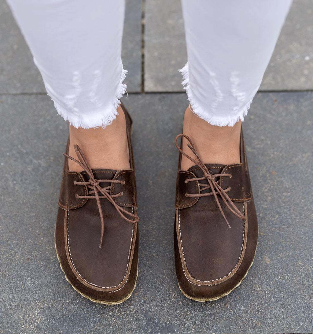 Earth women's barefoot leather boat shoe held in hand, sole and stitch detail