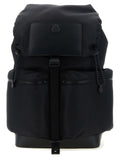 A black backpack with a top flap, two front zippered pockets, and a central vertical strap, photographed against a plain white background.