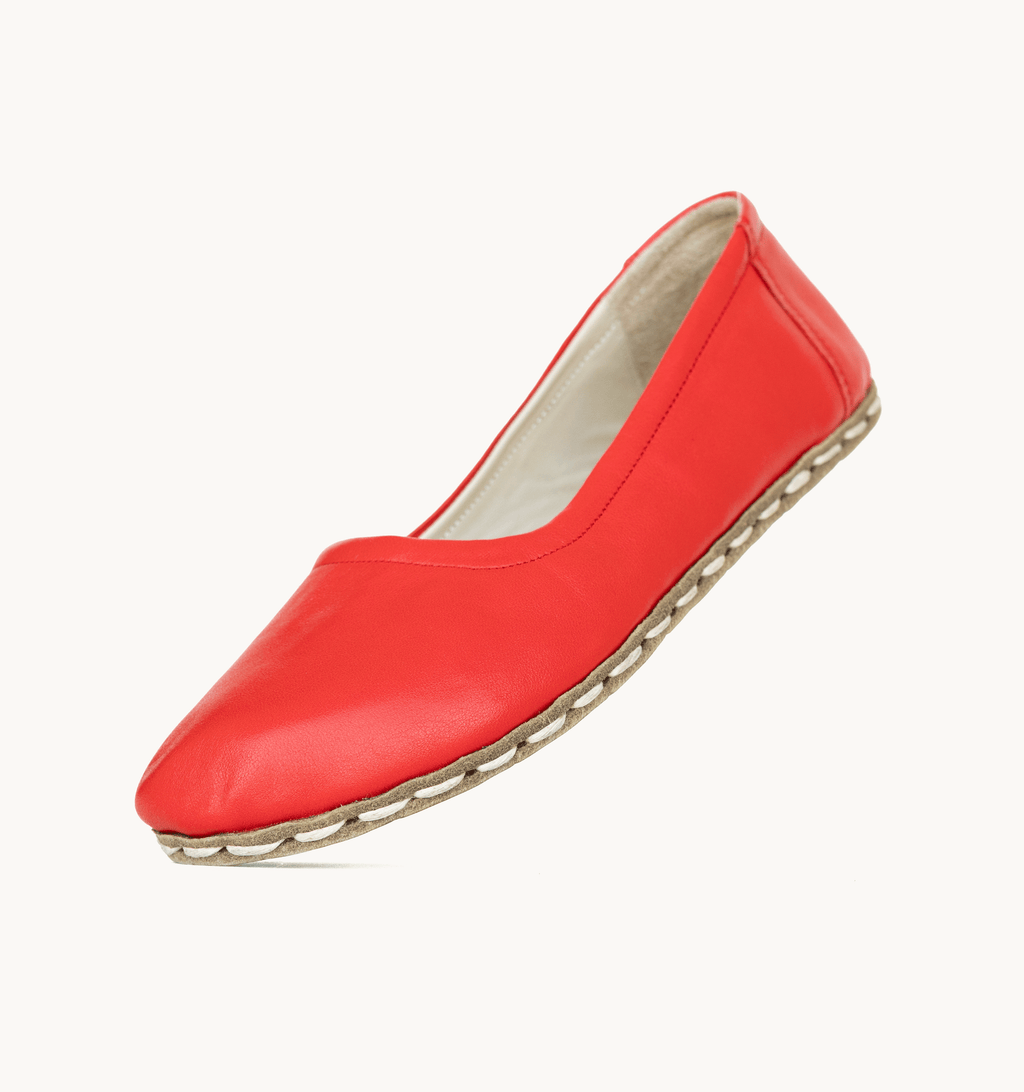 Crimson women's barefoot leather ballet flat held in hand, sole and stitch detail