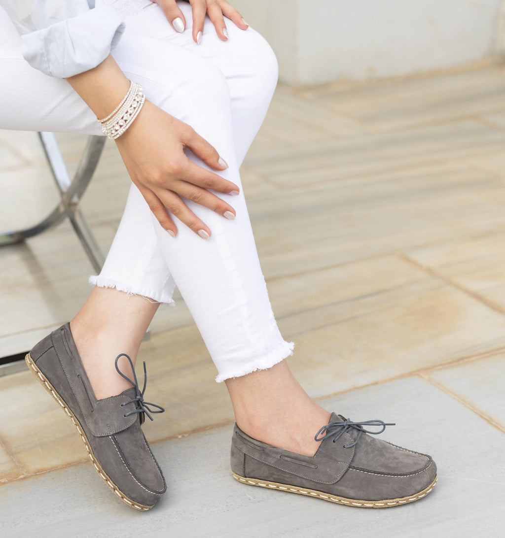 Ashen women's barefoot leather boat shoe held in hand, sole and stitch detail