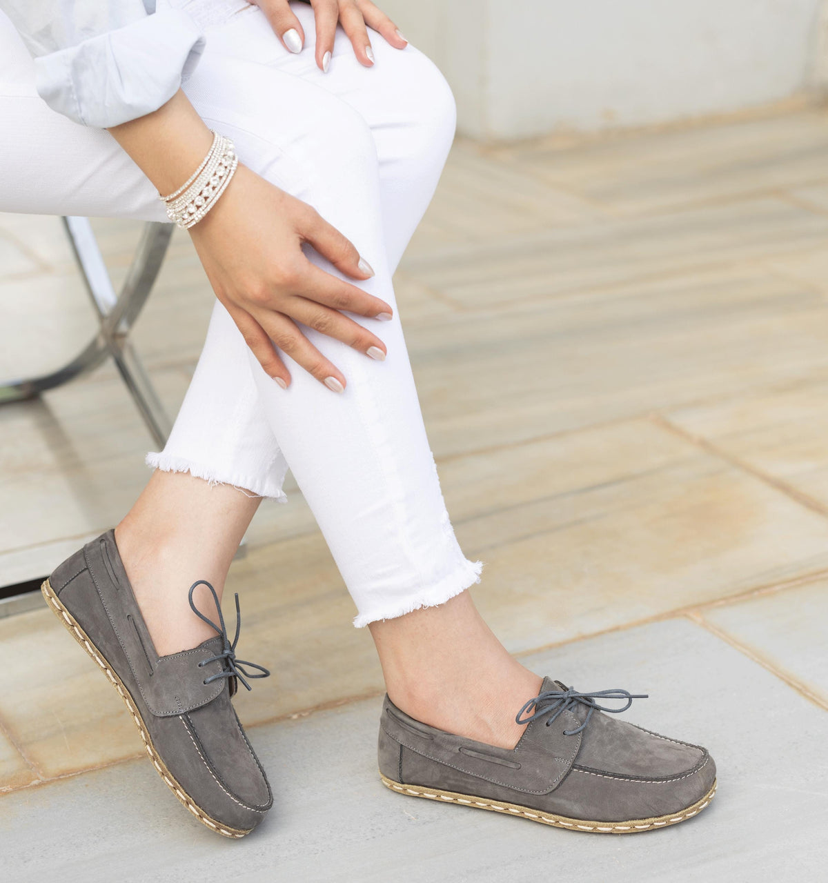 Ashen women's barefoot leather boat shoe held in hand, sole and stitch detail