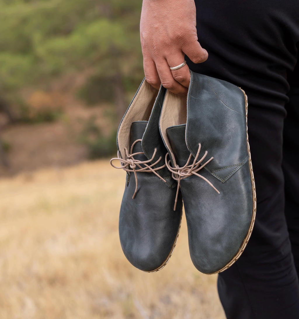 Evergreen men's barefoot leather chukka boot held in hand, sole and stitch detail