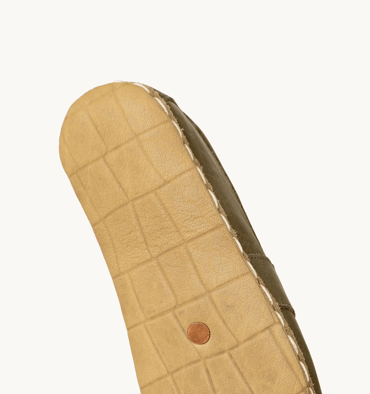 Olive women's barefoot leather penny loafer held in hand, sole and stitch detail