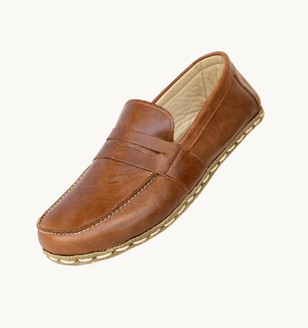 Russet women's barefoot leather penny loafer held in hand, sole and stitch detail