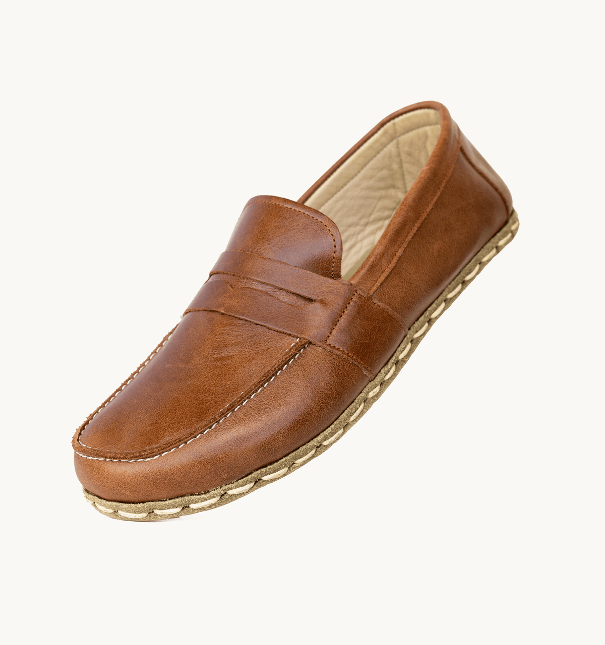 Russet women's barefoot leather penny loafer held in hand, sole and stitch detail