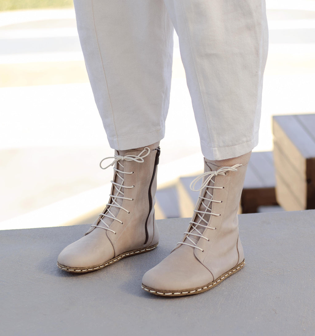 Sand women's barefoot leather ankle boot held in hand, sole and stitch detail