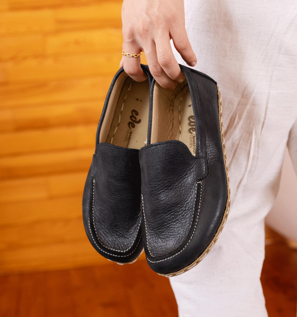 Raven Black women's barefoot leather moccasin held in hand, sole and stitch detail