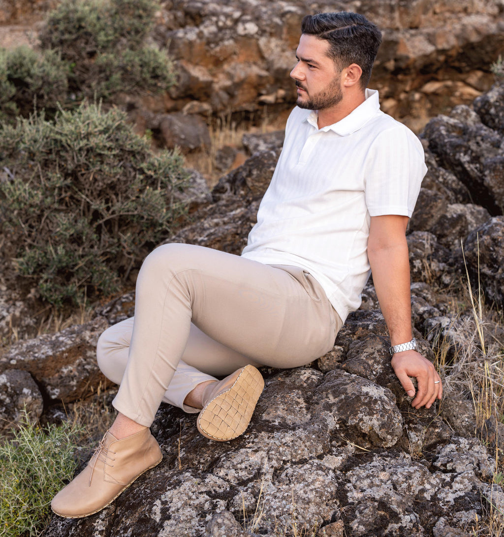 Sand men's barefoot leather chukka boot held in hand, sole and stitch detail