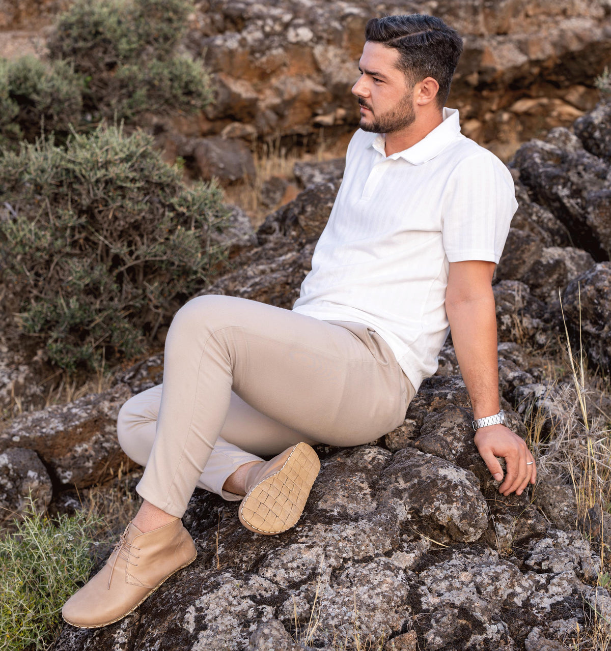 Sand men's barefoot leather chukka boot held in hand, sole and stitch detail