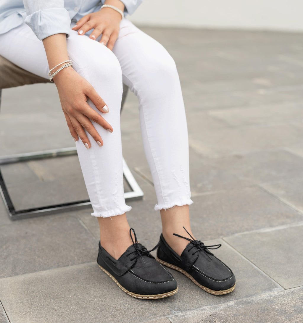 Raven Black women's barefoot leather boat shoe held in hand, sole and stitch detail