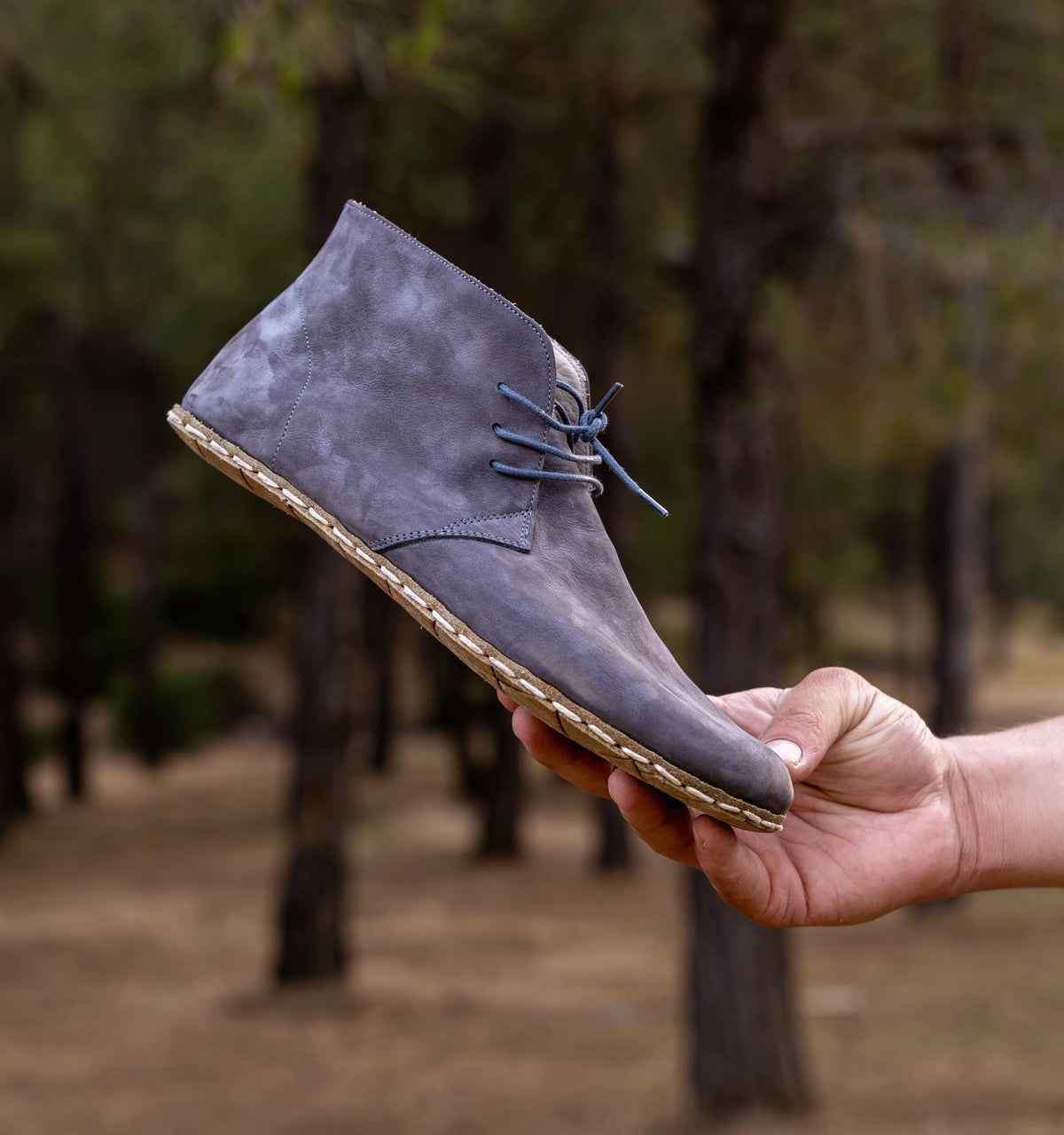 Ashen men's barefoot leather chukka boot held in hand, sole and stitch detail