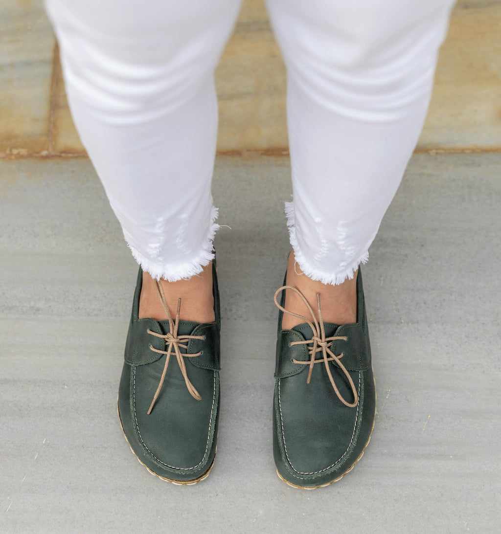 Evergreen women's barefoot leather boat shoe held in hand, sole and stitch detail
