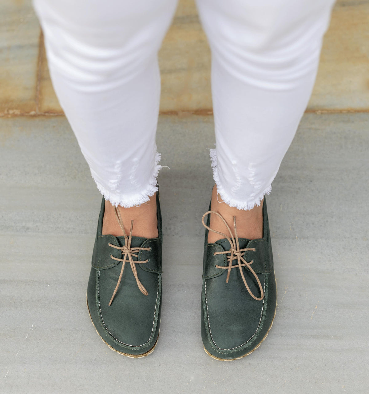 Evergreen women's barefoot leather boat shoe held in hand, sole and stitch detail