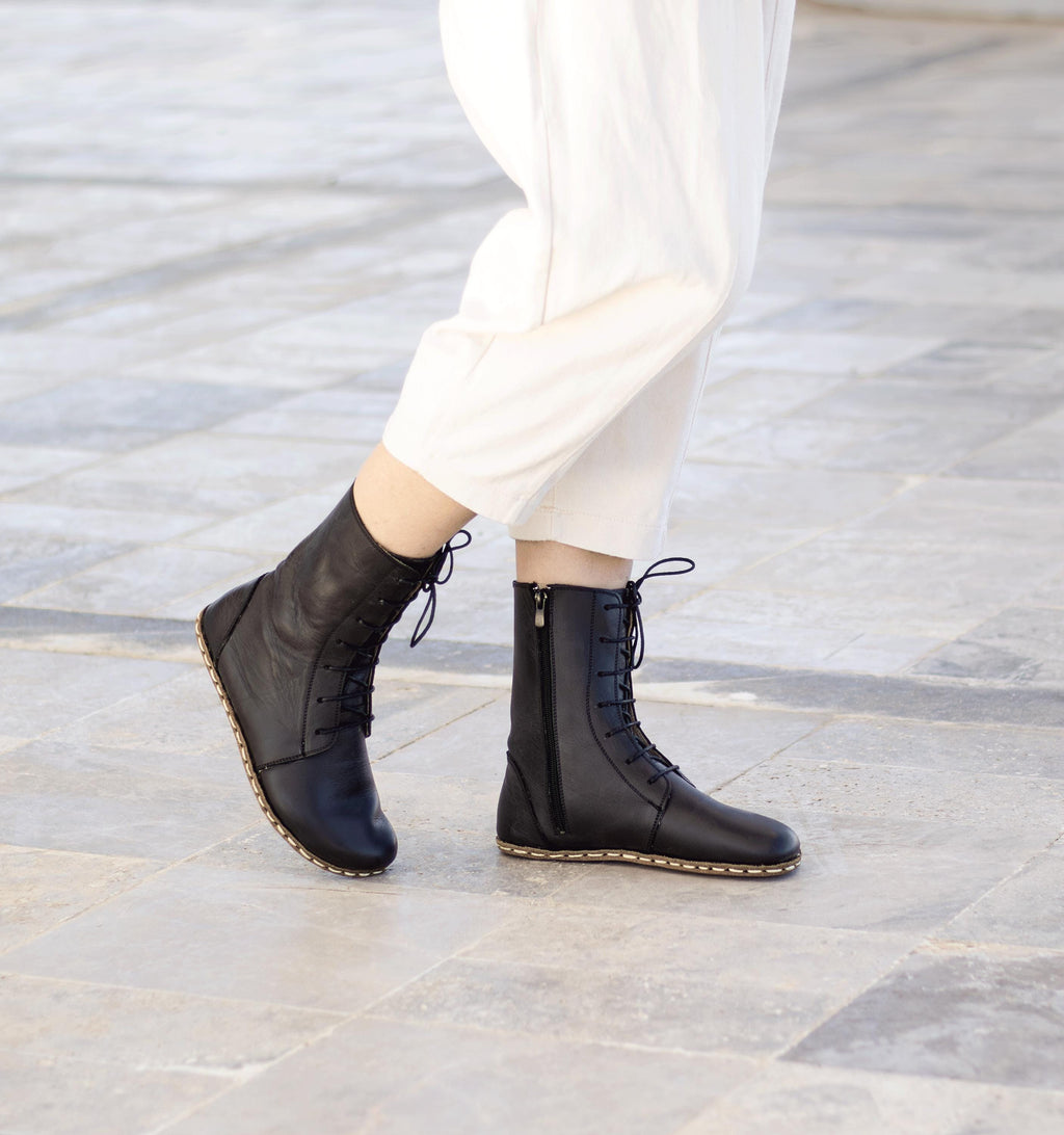 Raven Black women's barefoot leather ankle boot held in hand, sole and stitch detail