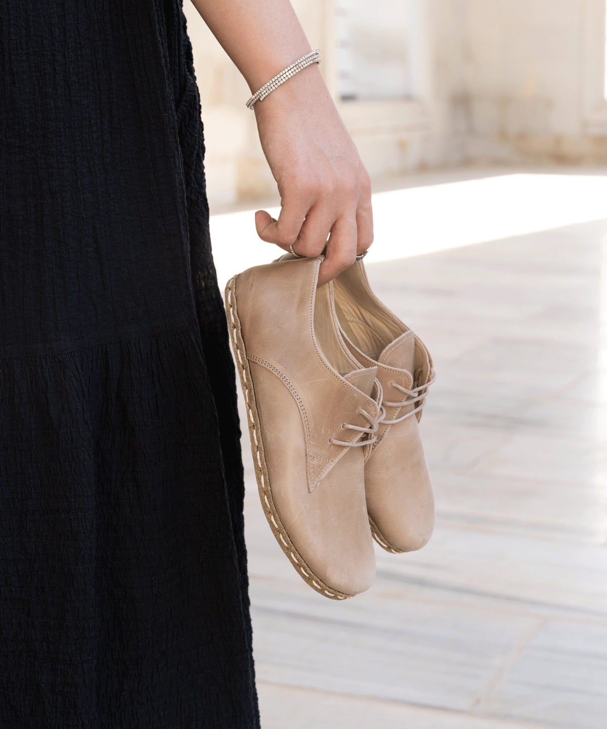 Sand women's barefoot leather oxford held in hand, sole and stitch detail