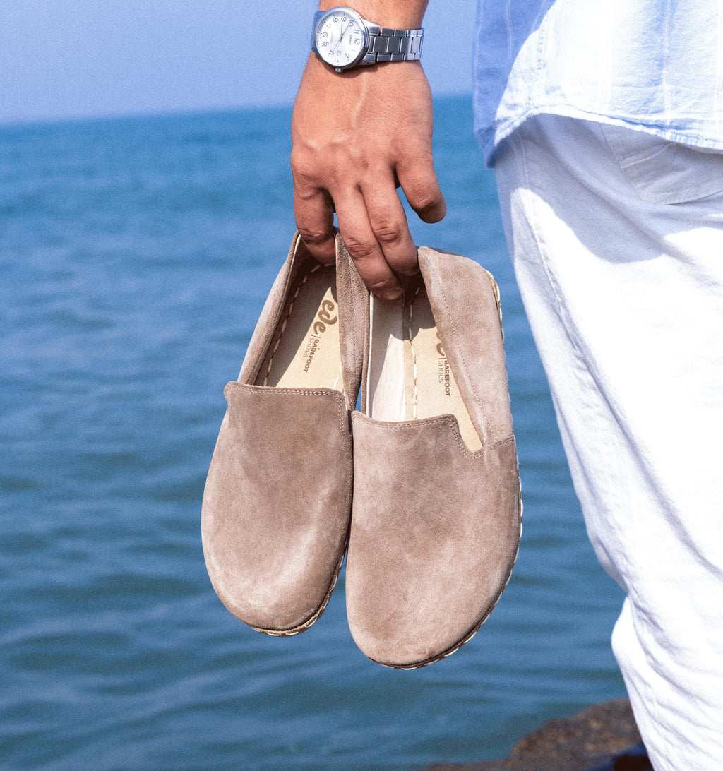 Beige Dawn men's barefoot leather loafer held in hand, sole and stitch detail