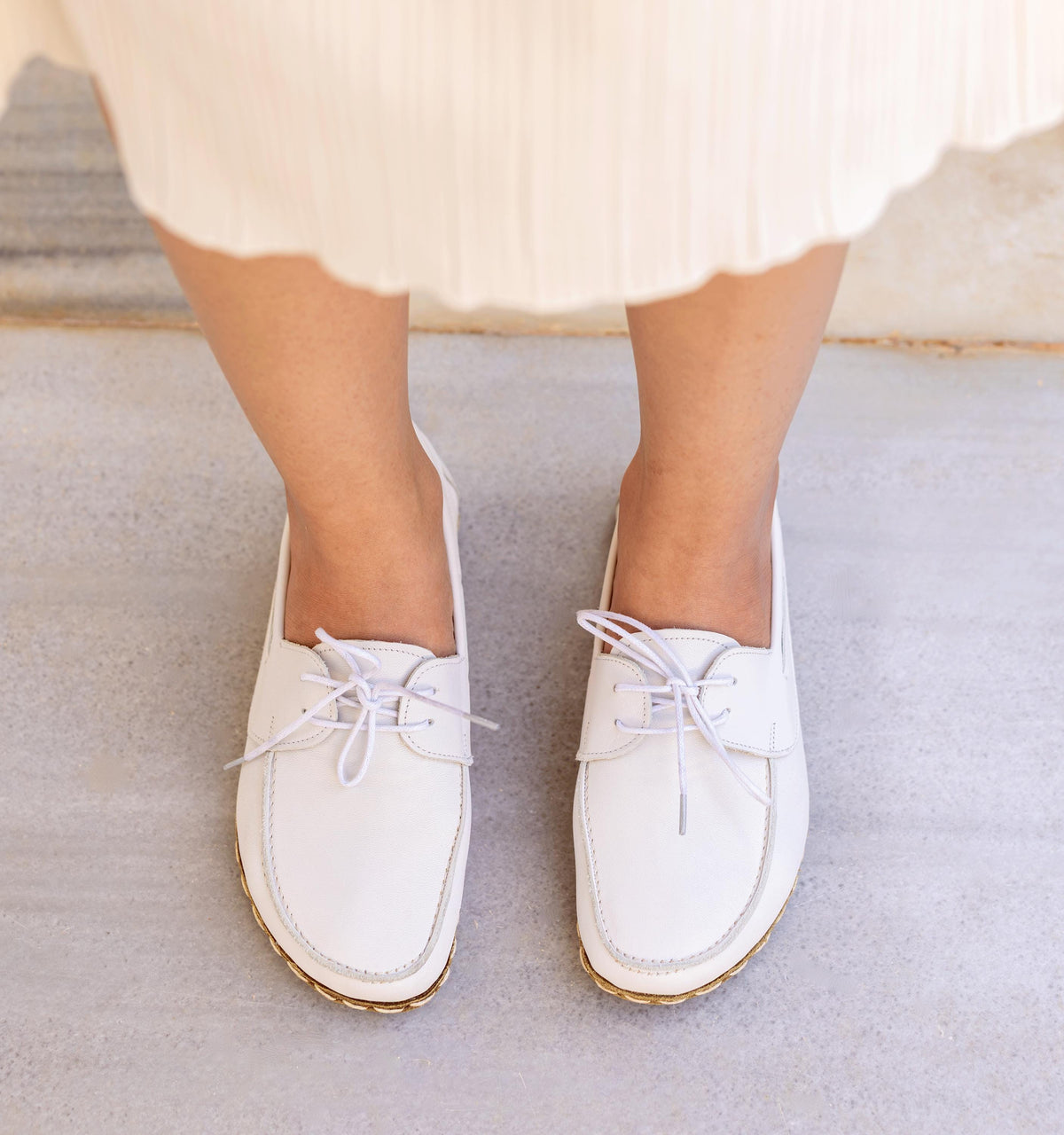 Cloud women's barefoot leather boat shoe held in hand, sole and stitch detail
