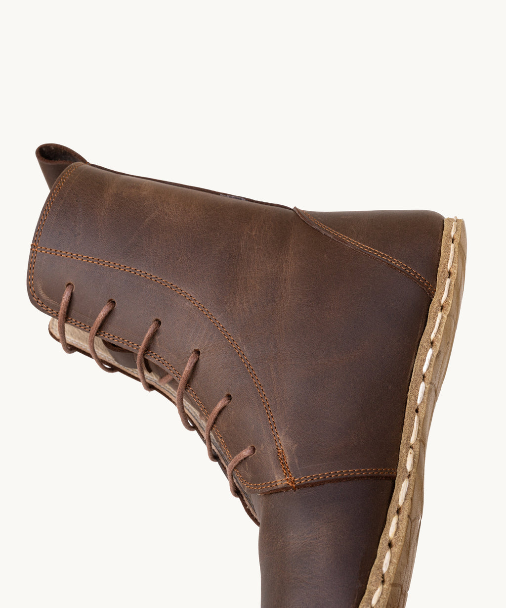 Earth women's barefoot leather tall lace-up boot held in hand, sole and stitch detail